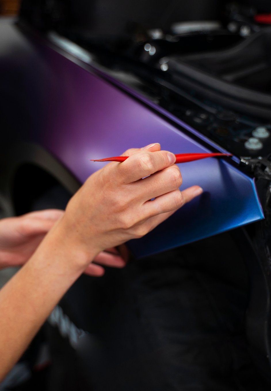 a car detailer correcting a paint job with a paint brush